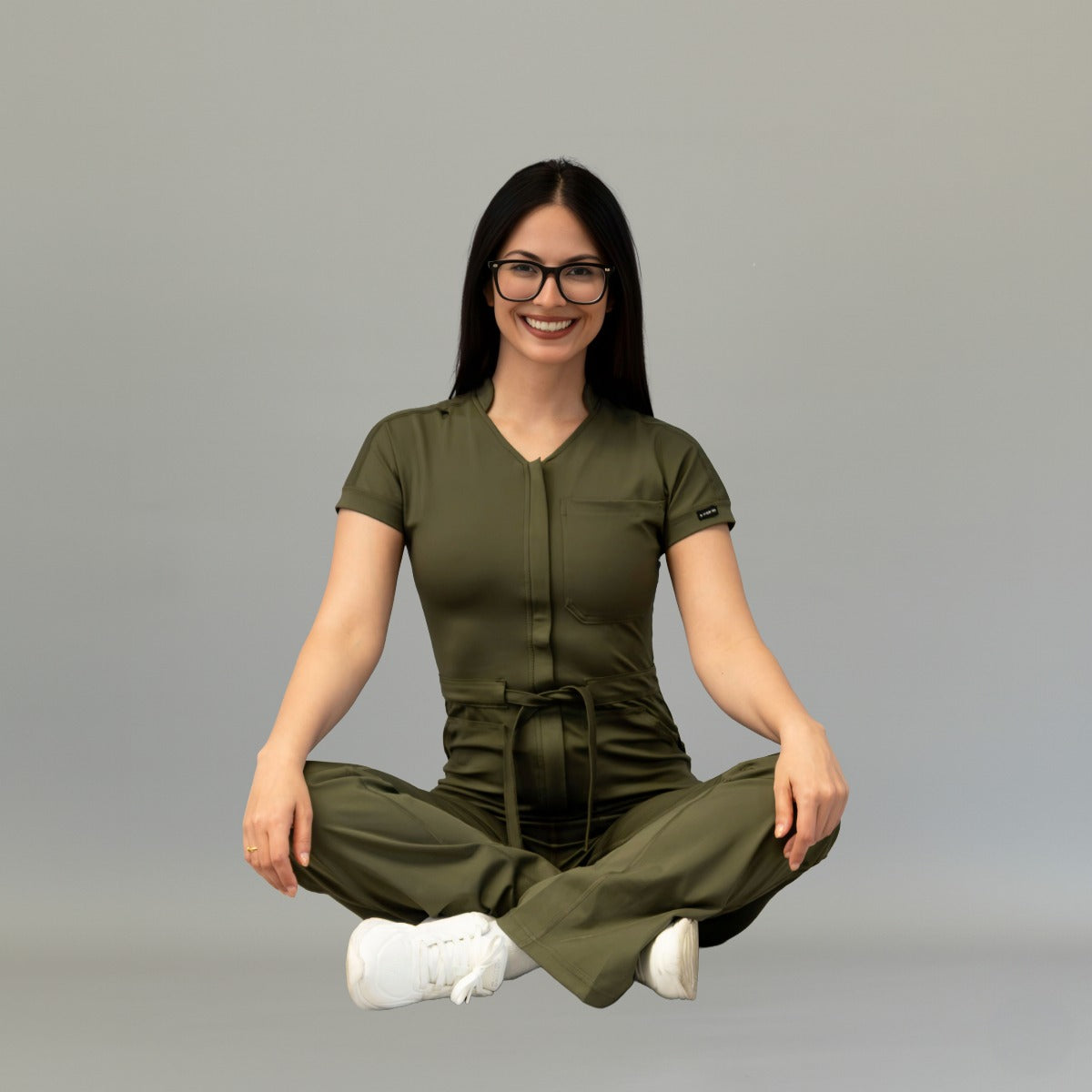 Modelo sentada con jumpsuit quirúrgico Verde Olivo flexible para mujer